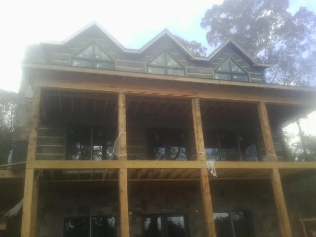 Dormers and porch framing on a large log home under construction — Roof Coating work by our crew in Hagaman