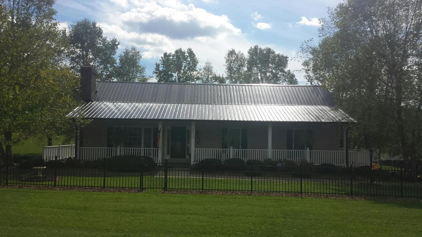 Gray metal roof on a brick ranch with a full width front porch — Gutter Guard Installation work by our crew in Hagaman