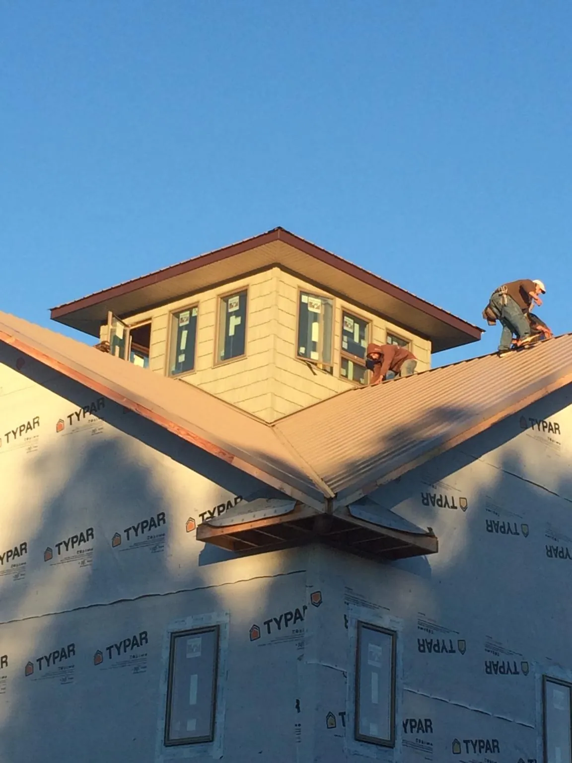 Roofers working around a rooftop cupola on a new metal roof at sunset — Roof Waterproofing in Hagaman by Roofing Brothers